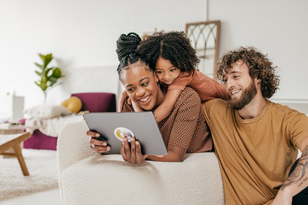 Padres e hija sonrientes en casa viendo juntos una película online